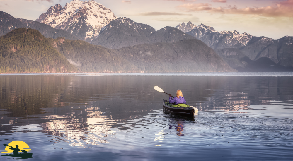 a lady is kayaking in the sea in front of mountain
