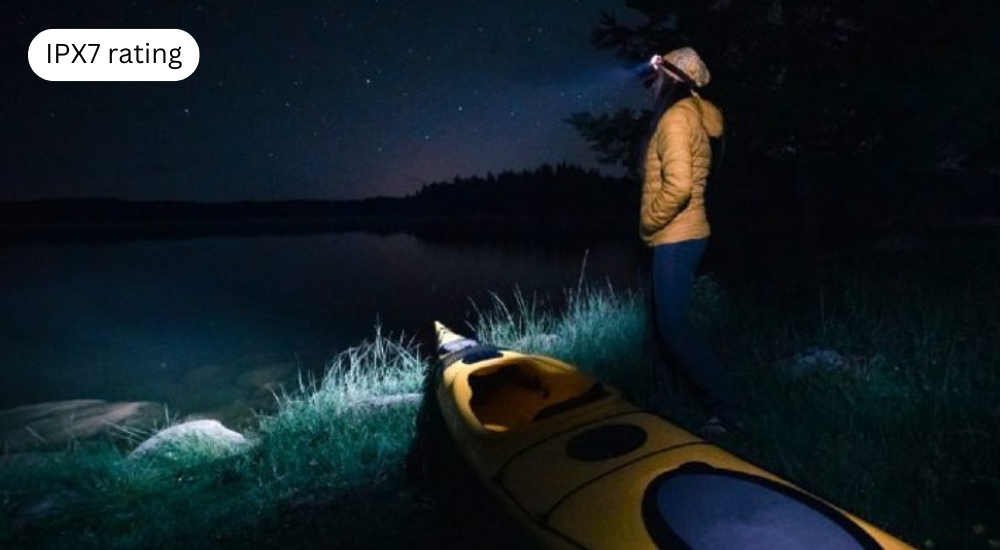 A lady is standing in front of a lake with a kayak